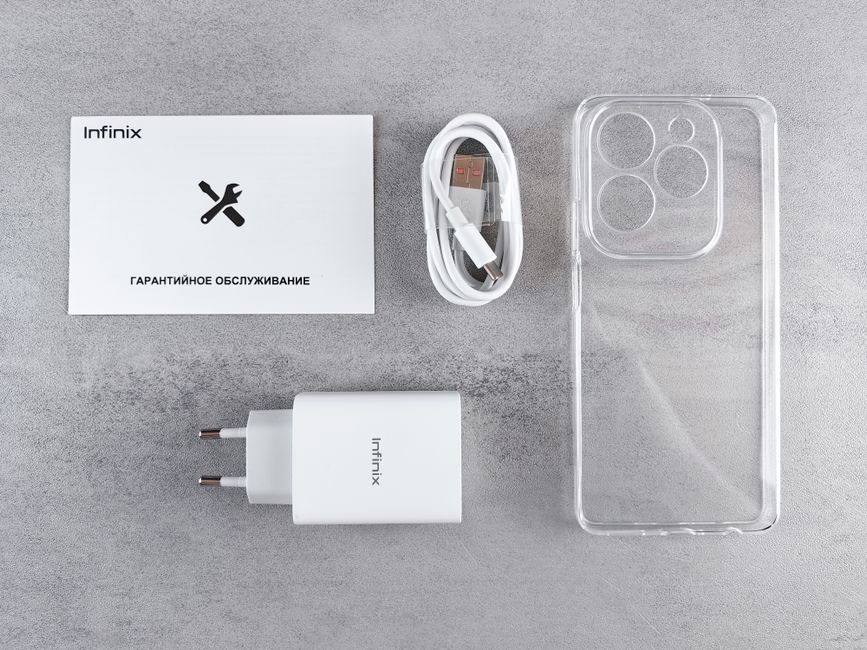 A white Infinix-branded phone charger with a two-pin plug, a matching white USB-C charging cable neatly coiled, a transparent plastic phone case, a small instruction booklet with the Infinix logo and 
